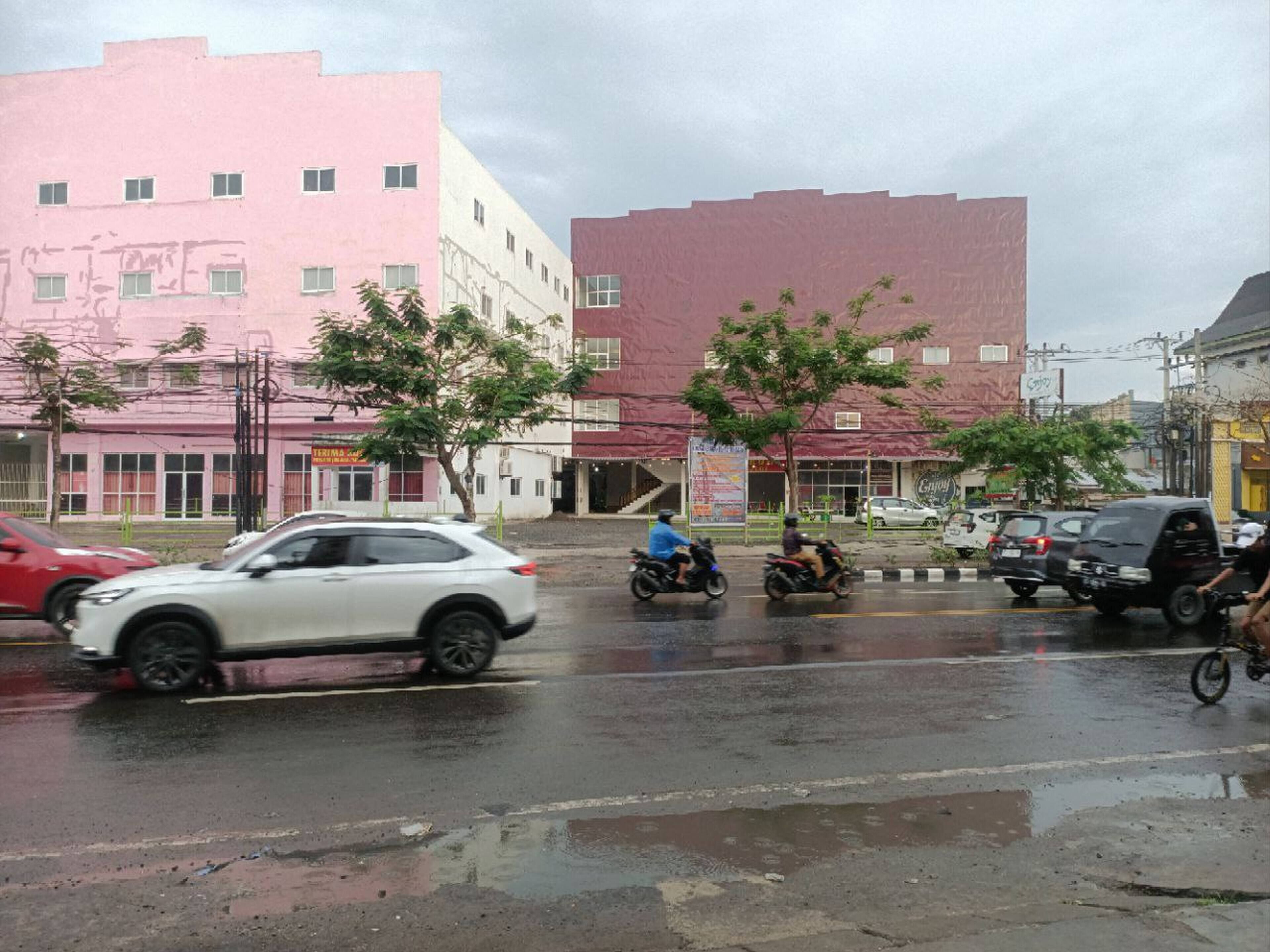 A street scene with buildings, vehicles, and trees.