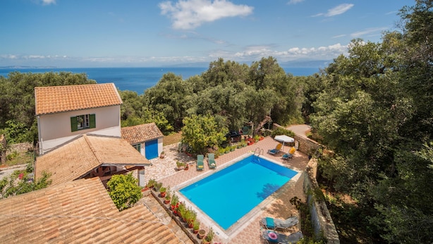 Une piscine entourée d’un jardin avec vue sur la mer.