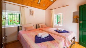 Une chambre avec deux lits, un plafond en bois et une porte verte.