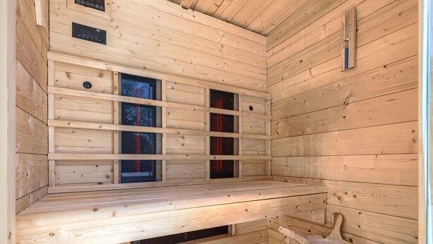 Una sauna con paredes de madera, un banco, un cubo y una cuenca de piedra.