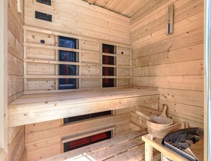 A sauna room with wooden walls, a bench, a bucket, and a stone basin. - Villa Lora by Interhome (Kršan)