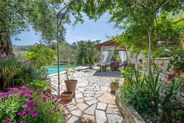 A stone patio with potted plants and a gazebo.