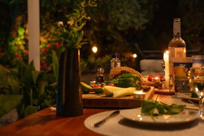 A table set for a meal with a bottle, candles, and a variety of fruits and vegetables. - Georgina House in Velianitatika (Paxos)