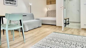 Moderni olohuone, jossa on sohva, ruokapöytä ja tuoli, kuviollinen matto ja seinällä oleva kehystetty taulu.