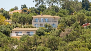 Un edificio a due piani con balconi, immerso nel verde e alberi.