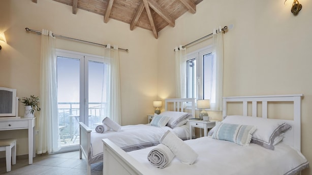 Camera d'albergo con due letti, una scrivania con una sedia, una televisione e vista sul balcone.
