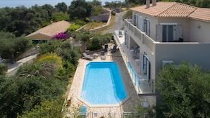 Un edificio a due piani con piscina, area salotto esterna e vista sul mare.