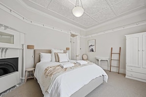 Ein Schlafzimmer mit einem Bett, einem Kamin, einem Kleiderschrank und einer Leiter.