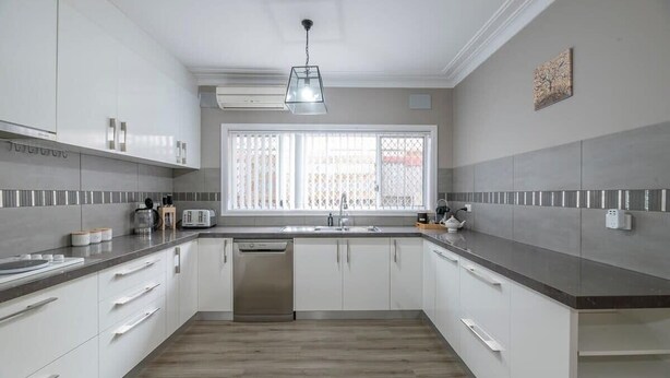 Una cocina moderna con armarios blancos, lavavajillas de acero inoxidable y una ventana con vistas.