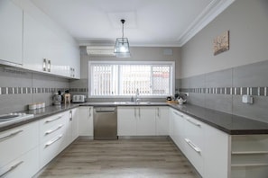 A modern kitchen with white cabinets, a stainless steel dishwasher, and a window with a view.