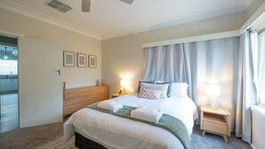 Habitación de hotel con cama, mesitas de noche, ventilador de techo y vistas al exterior.