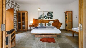 Une chambre à coucher avec une tête de lit en bois, un lit recouvert de linge de lit blanc, un tapis rouge et des meubles en bois.