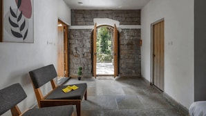 Un couloir aux murs de pierre, une porte en bois et un banc.