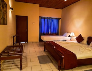 A hotel room with a large bed, a bench, a chair, and a door. - Crystal Villa (Galle)