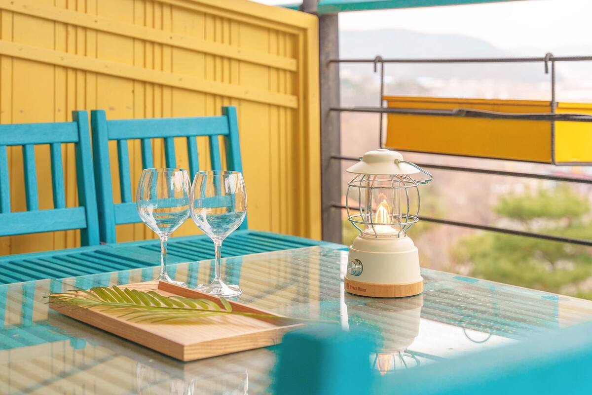 A table with two clear glasses, a wooden tray, and a white lantern.