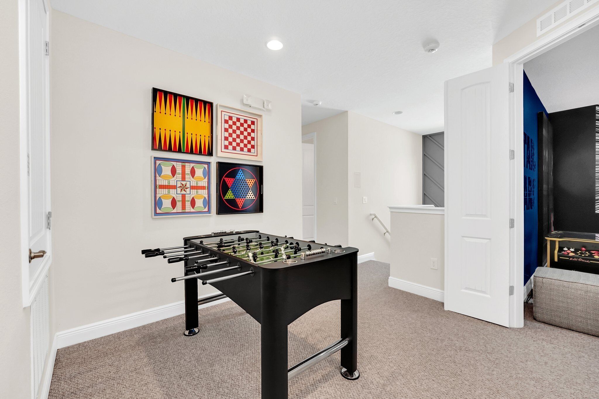 A room with a foosball table, a door, and wall art.
