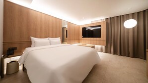 Ein modernes Hotelzimmer mit einem großen Bett, einem flachbildfernseher an der Wand, einem Nachttisch mit Lampe und einer Wandverkleidung aus Holz.