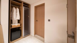 Ein begehbarer Kleiderschrank mit aufgehängten Roben, einem Korbwäschekorb und einer schwarzen Aufbewahrungsbox.