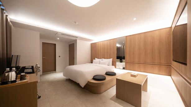 Ein modernes Hotelzimmer mit einem großen Bett, einem Holztisch und einem Flachbildfernseher.