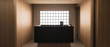 Un comptoir d’accueil avec une grande fenêtre, une plante en pot et un panneau indiquant la présence d’un café, d’un restaurant et d’un pub.