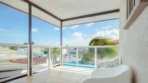 En rummelig balkon med pool, store vinduer og en hvid stol.