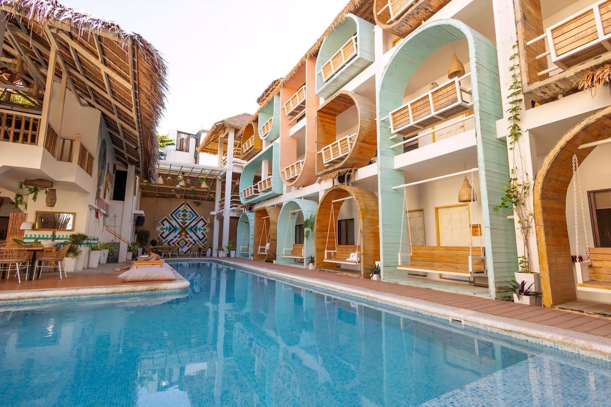 A pool area with multiple levels of balconies and a thatched roof structure.