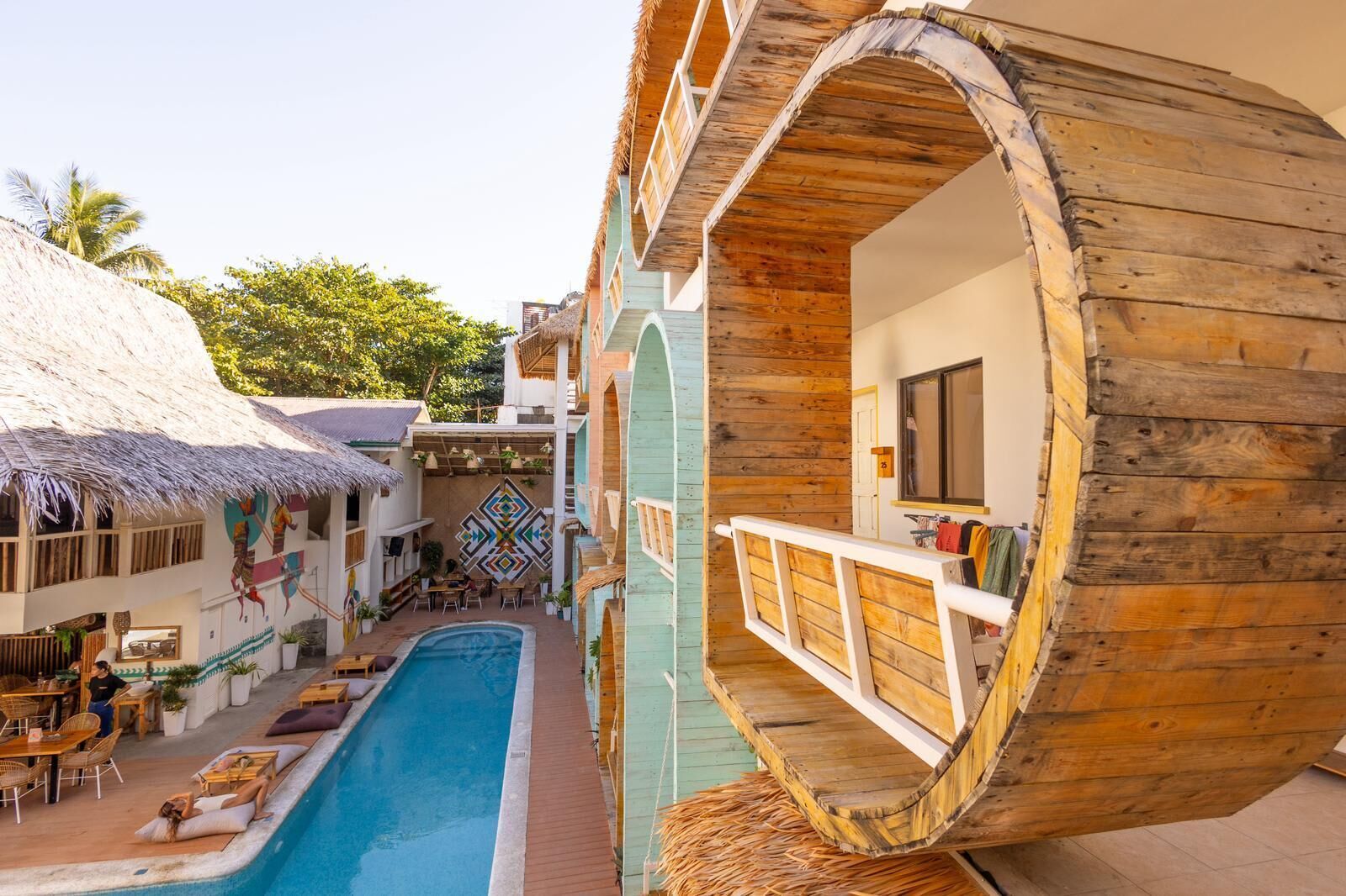 A resort with a pool, wooden structures, and a thatched-roof building.