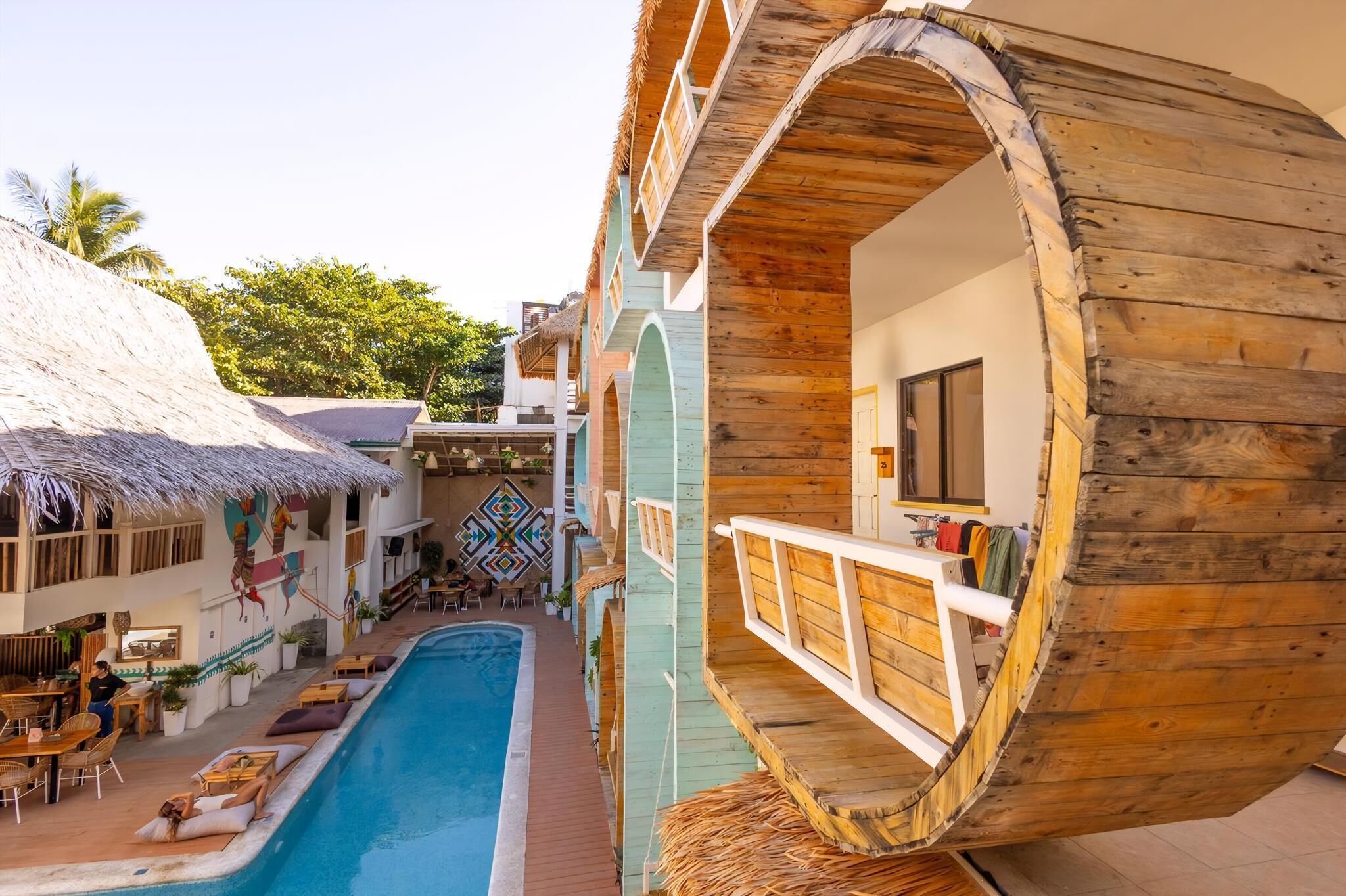 A resort with a pool, wooden structures, and a thatched-roof building.