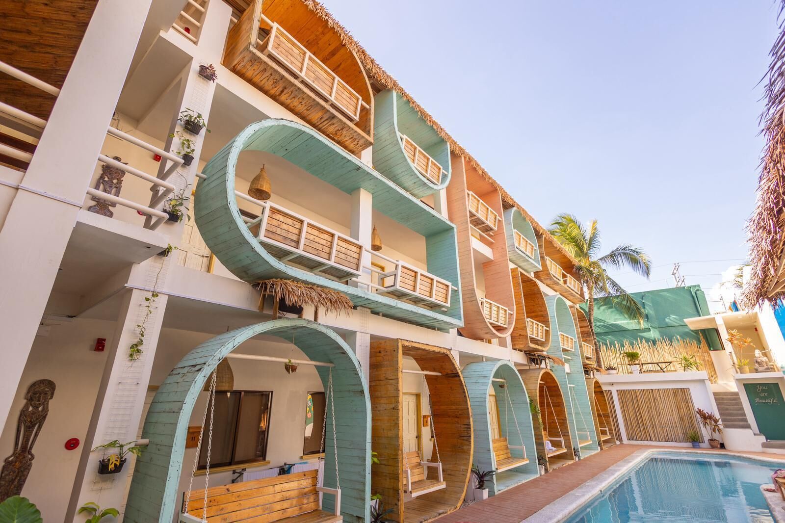 A multi-story hotel with balconies, a swimming pool, and outdoor seating areas.