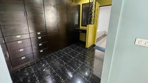 Une pièce avec des meubles de rangement en bois foncé, un sol carrelé noir et un mur d’accent jaune.