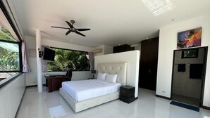 Une chambre moderne avec un grand lit, un ventilateur de plafond, un bureau avec une chaise et un téléviseur.