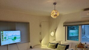 A modern bedroom with a bed, a TV mounted on the wall, a ceiling light, and a window. - Steps away from DDP, Airport Bus, DongDaeMun Shopping Malls [Timeless Rooftop] (Seoul)