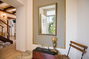 Eine Treppe führt zu einer Empfangshalle mit einem Spiegel, einem Willkommensschild und einer Trophäe auf einer Kommode.