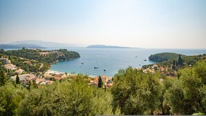 A coastal town with boats on the water, surrounded by greenery and hills. - Penelope Stone House (Corfu)