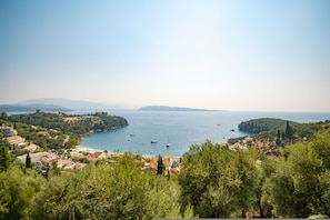A coastal town with boats on the water, surrounded by greenery and hills. - Penelope Stone House (Corfu)