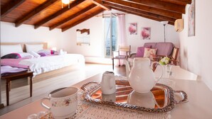 A cozy room with a wooden ceiling, a bed with white bedding, a table with a tray holding a teapot, a cup, and a pitcher. - Penelope Stone House (Corfu)