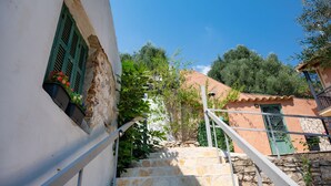 A stone staircase leading up to a building with a green door and window shutters. - Penelope Stone House (Corfu)