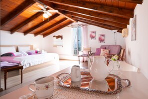 A cozy room with a wooden ceiling, a bed with white bedding, a table with a tray holding a teapot, a cup, and a pitcher. - Penelope Stone House (Corfu)
