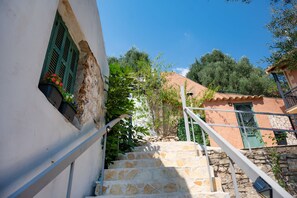 A stone staircase leading up to a building with a green door and window shutters. - Penelope Stone House (Corfu)