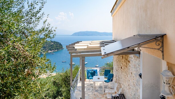 A terrace with a view of the sea, stone flooring, and outdoor furniture. - Penelope Stone House (Corfu)