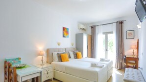 Ein Hotelzimmer mit Bett, Nachttisch, Sessel, Schreibtisch und Fernseher.