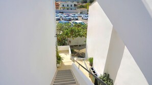 A view from a balcony overlooking a parking lot with several cars, a staircase, and some greenery. - Angela Apartment in Kassiopi (Corfu)