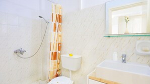 A bathroom with a shower, toilet, sink, and a mirror above the sink. - Angela Apartment in Kassiopi (Corfu)