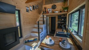A compact wooden cabin interior with a staircase, a kitchen area, and a dining space. - Chipmunk Tiny Home at The Woolly Bugger Inn (Estes Park)