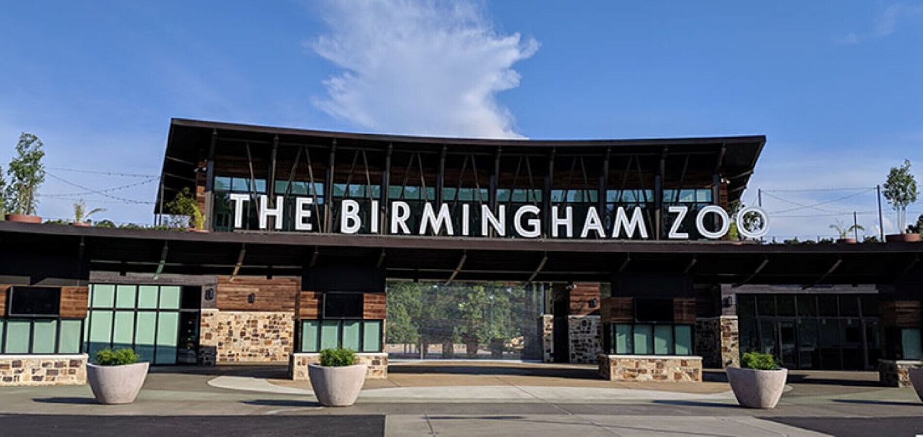 The exterior of The Birmingham Zoo with a modern architectural design, featuring large windows and stone accents.