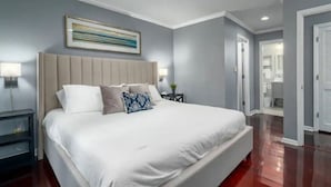 Un dormitorio moderno con una cama grande, cabecera, mesitas de noche y un cuadro enmarcado en la pared.