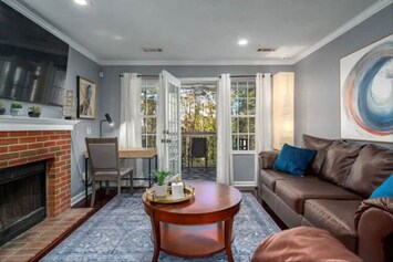 Plush living room with patio access and dedicated work space, featuring flat-screen TV.