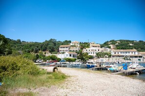 A coastal marina with boats docked, surrounded by hillside buildings and greenery.