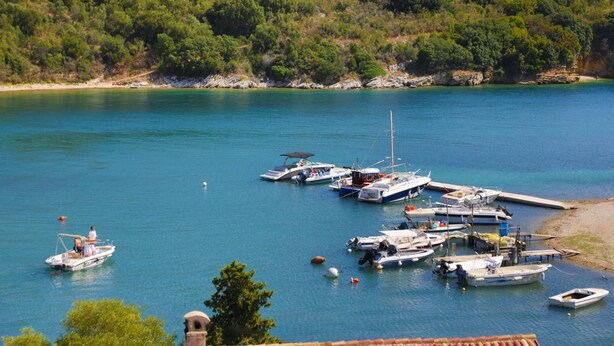 A marina with boats docked, surrounded by greenery and hills. - Spiros Saint Stephanos (Corfu)