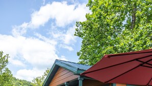 A lodge with a porch, outdoor seating, and a view of a lake. - Cabin 3 - Everything you need in this Cabin for a great weekend. (Connellsville)